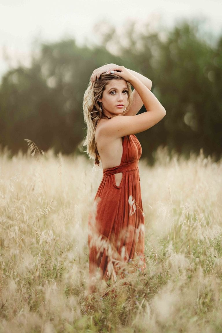 Senior girl posing in a field of wheat
