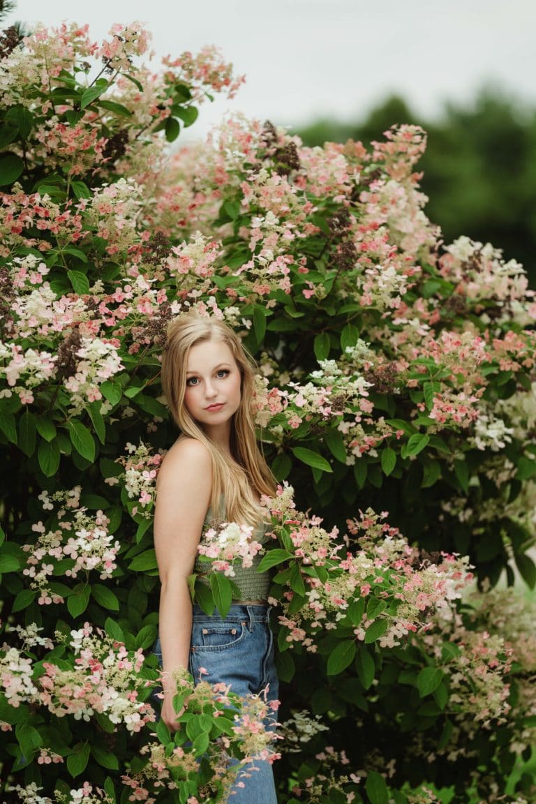Nature Minneapolis Senior Pictures with girl standing in flowering bush. Captured by Minnesota Senior Photographer Any Angle Photography.