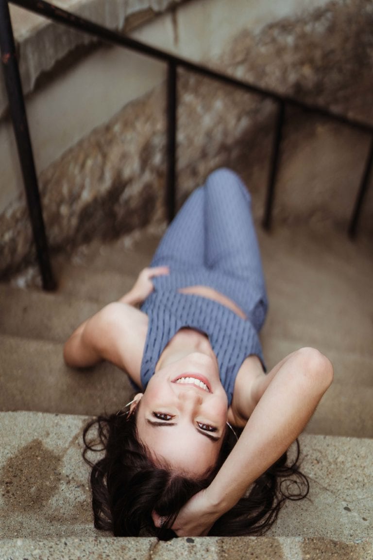 girl lying on stairs smiling with hand in hair.