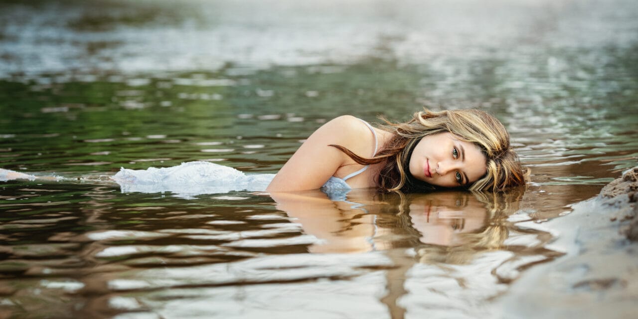Senior pictures with girl lying in water at Boom Island Park in Minneapolis. Captured by Minnesota Senior Photographer Any Angle Photography.