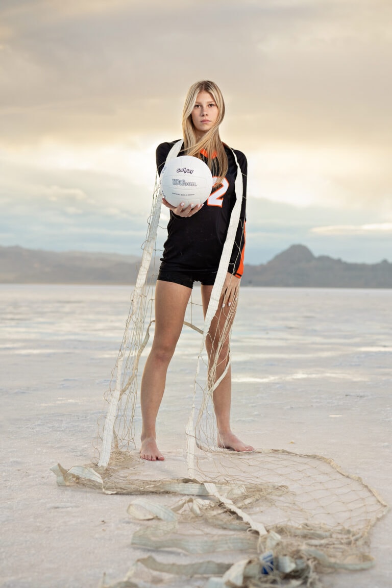 Senior pictures with girl holding volleyball on Bonneville Salt Flats at Sunset. Captured by Utah Senior Photographer Any Angle Photography.