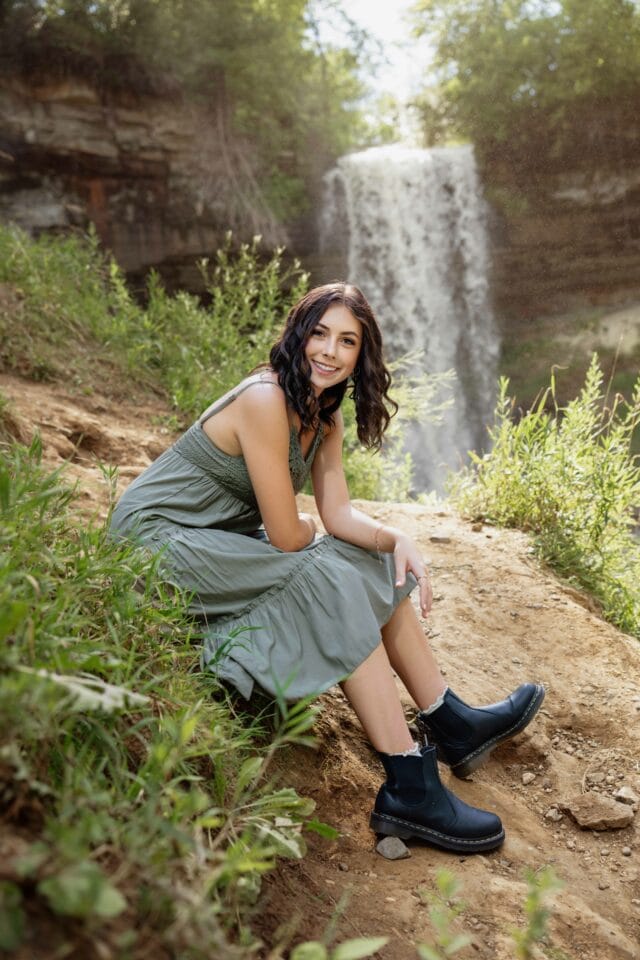 Senior pictures with girl in green dress in front of Minnehaha Falls in Minnesota.