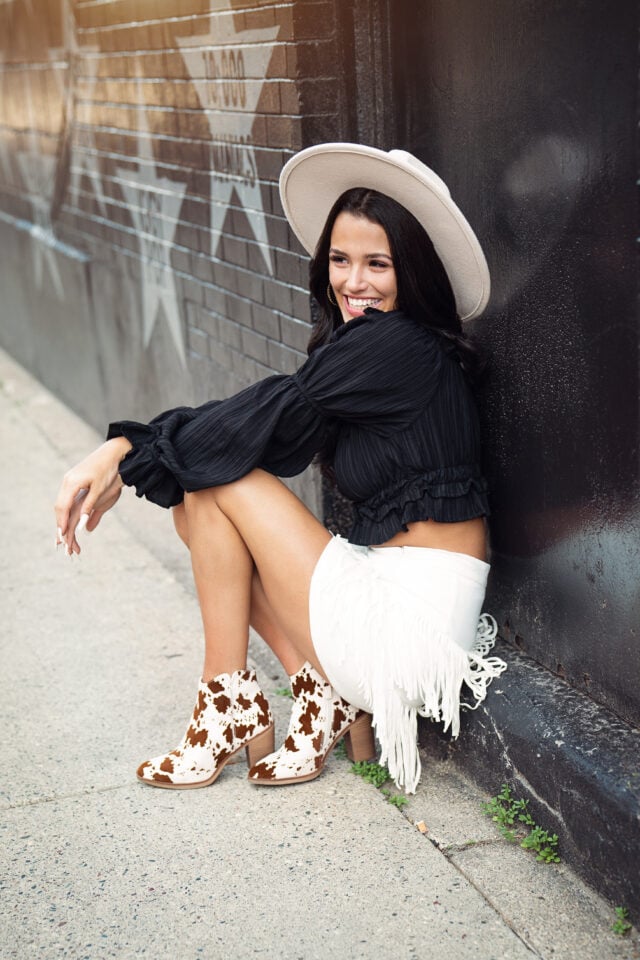 Urban Senior pictures with girl in cowboy outfit in downtown Minneapolis by star wall. Captured by Minnesota senior photographer Any Angle Photography.