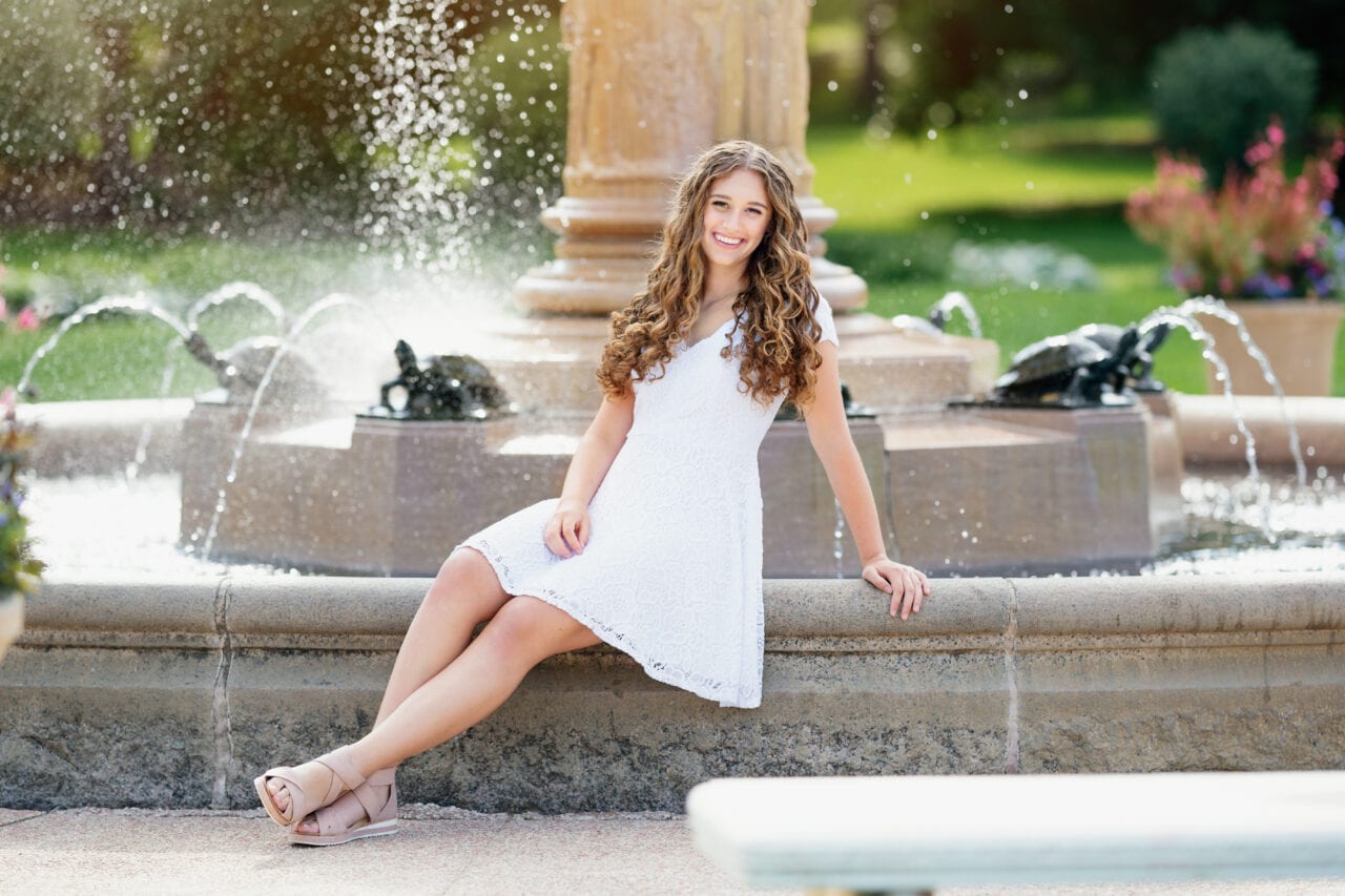 Senior pictures with girl in front of fountain and Lyndale Rose Garden in Minneapolis. Captured by Minneapolis senior photographer Any Angle Photography.